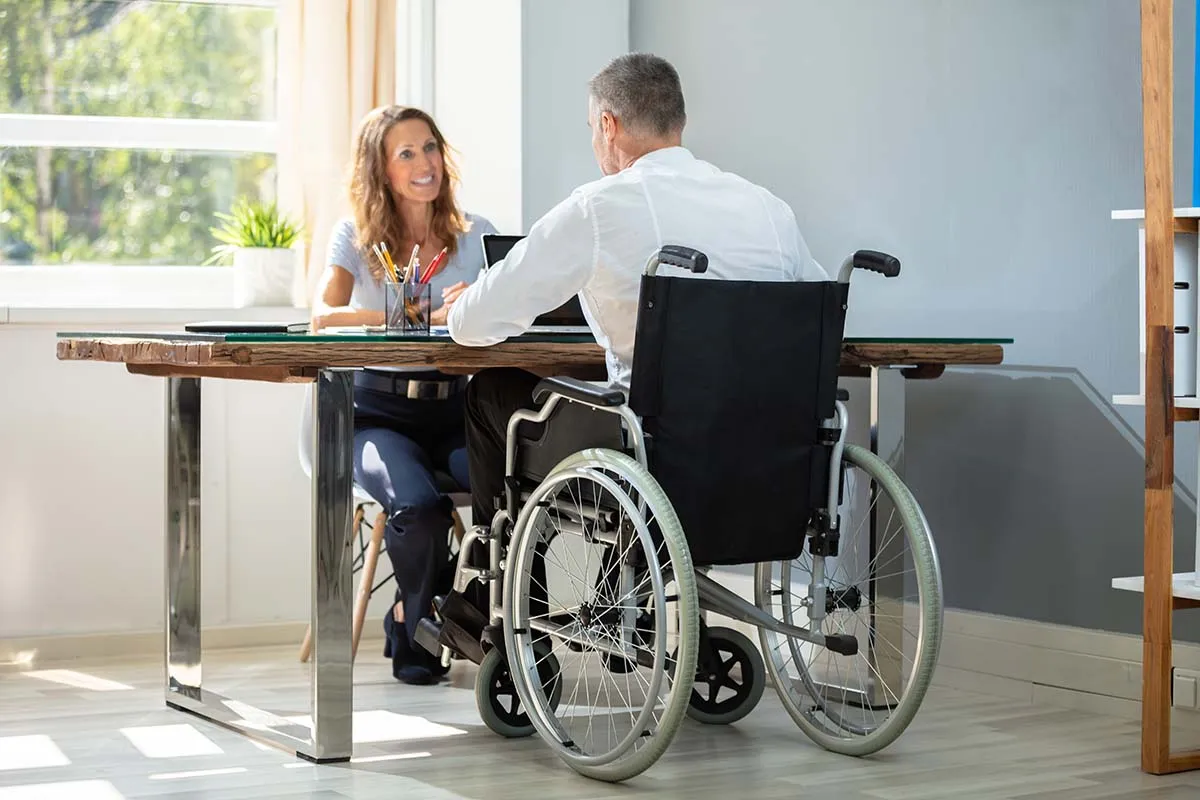 Why-Occupational-Therapists-are-Ideal-for-Home-Assessments Man in wheelchair sitting at table meeting with a therapist